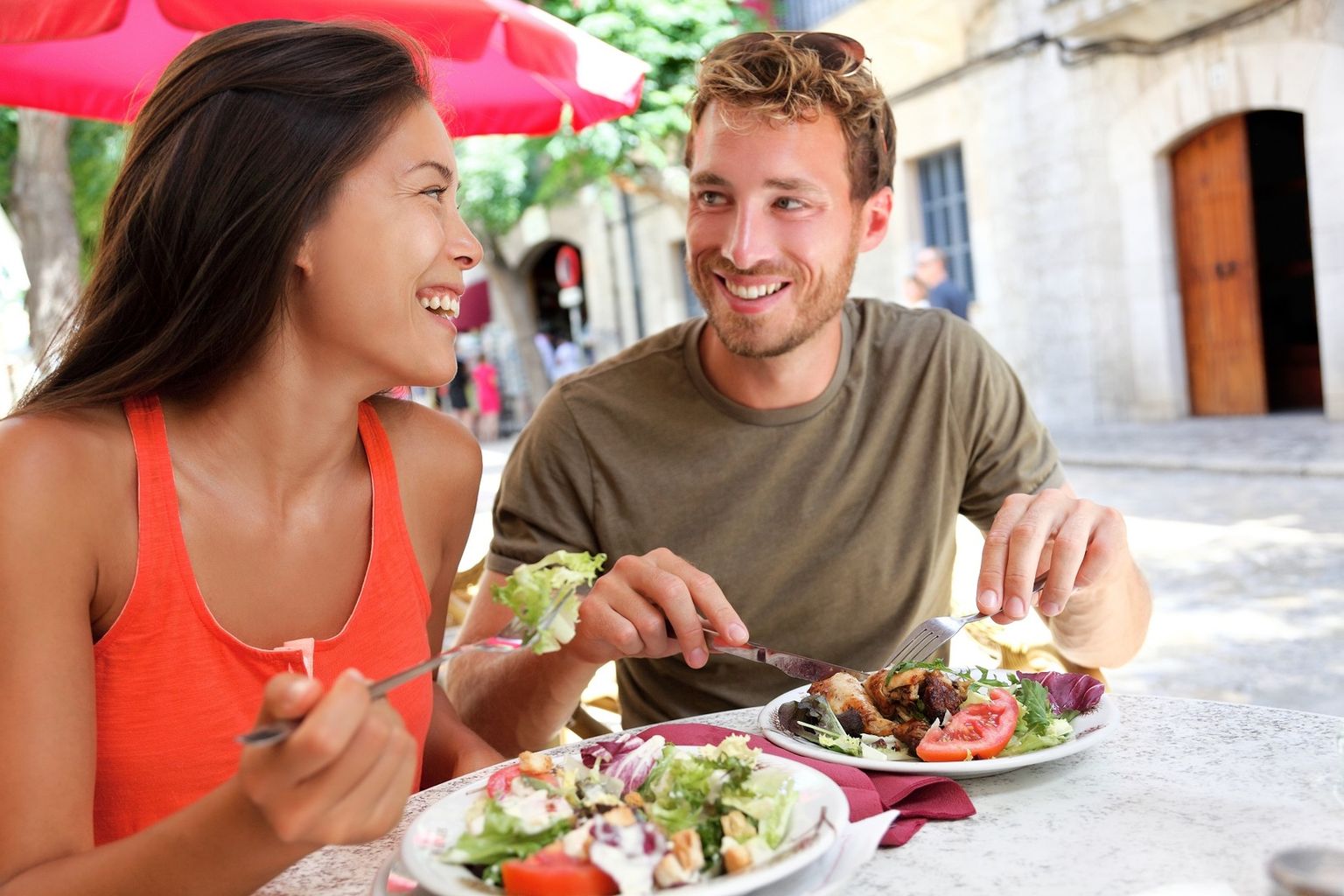 Two people eating in a restaurant and smiling at each other.
